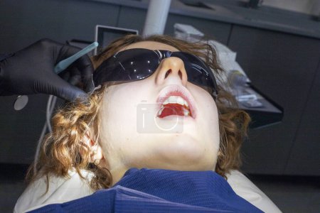 Téléchargez les photos : Fille au rendez-vous chez le dentiste avec la bouche ouverte. Traitement orthodontiste et soins dentaires - en image libre de droit