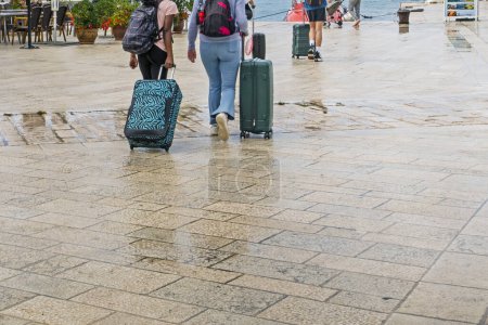 Téléchargez les photos : Touristes avec des valises sur le remblai. Réfugiés - en image libre de droit