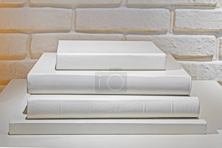 stack of white books on a white wall background. Education and