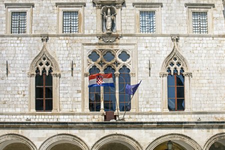 ancient windows with and sculptures in an ancient building with the flag of Croatia and NATO of Roman masonry