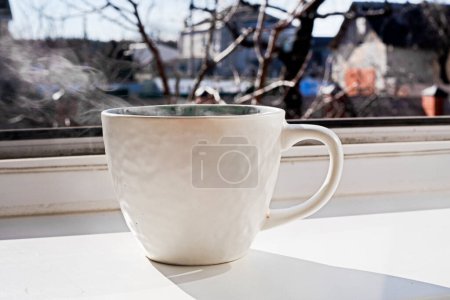 Eine Schüssel Heißgetränk mit Tee oder Kaffee steht auf der Fensterbank. Ruhetag und covid 19