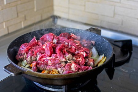 Téléchargez les photos : Viande fraîche crue coupée en morceaux dans une poêle. Cuisiner à la maison dans la cuisine - en image libre de droit