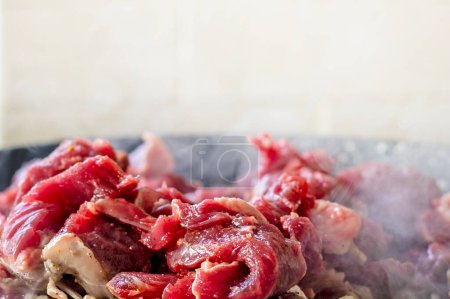 Photo for Cook raw fresh meat cut into pieces in a frying pan. Cooking at home in the kitchen - Royalty Free Image