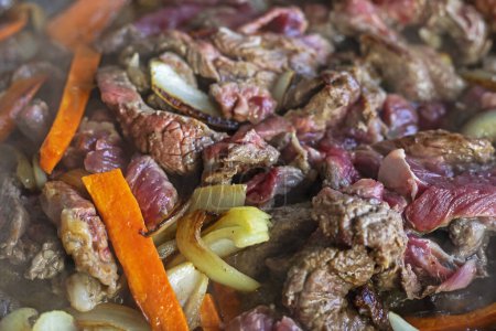 Téléchargez les photos : Cuire la viande fraîche crue coupée en morceaux dans une poêle avec des légumes, vue du dessus - en image libre de droit