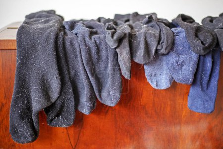 gewaschene schwarze Männersocken in Wolle auf dem Kleiderschrank