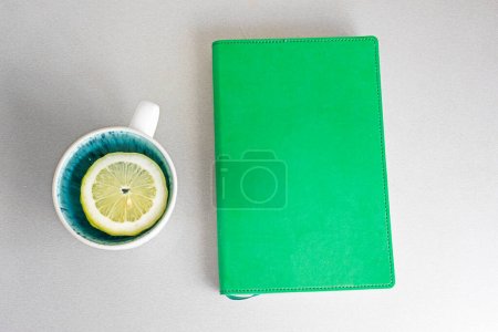 Foto de Planificador semanal en la mesa junto a una taza de limón. Buenos días, empanado del día, semana, mes, año - Imagen libre de derechos