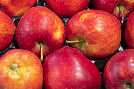 red apples lie in a container in a supermarket