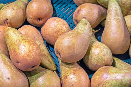 ripe juicy pears lie in a container in a supermarket