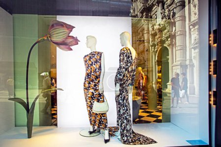 Schaufensterpuppen in stilvollen langen Kleidern mit Blumen auf einem Geschäft windo