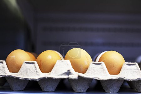 primer plano de los huevos de pollo marrón de granja en recipientes de cartón en un mostrador de la tienda