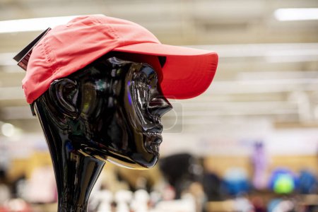 red sports cap on the head of a black mannequin in a sports store