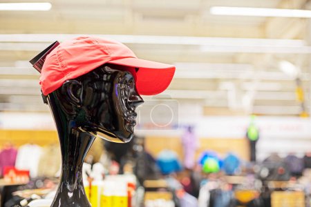 red sports cap on the head of a black mannequin in a sports store