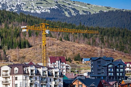 Téléchargez les photos : Construction d'hôtels et de maisons près des montagnes. station de ski loisirs actifs - en image libre de droit