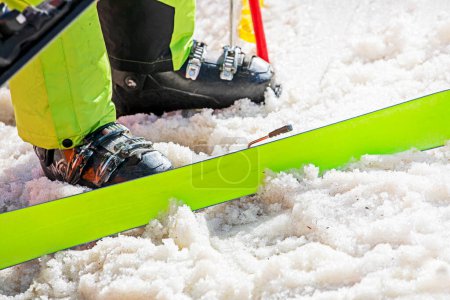 esquiador se pone botas de esquí en una pista nevada. vacaciones activas con la familia