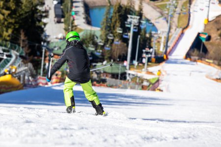 skieur garçon dans un casque vert descend de la montagne dans le style de sculpture. Loisirs familiaux actifs