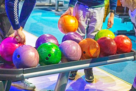 choisir des boules multicolores selon leur lourdeur pour le jeu de bowling. Vacances actives en famille