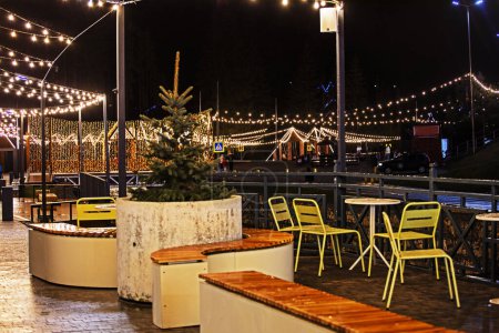 Foto de Cafetería iluminada con guirnaldas luminosas en el exterior por la noche. Vacaciones en familia - Imagen libre de derechos