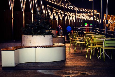 Foto de Cafetería iluminada con guirnaldas luminosas en el exterior por la noche. Vacaciones en familia - Imagen libre de derechos
