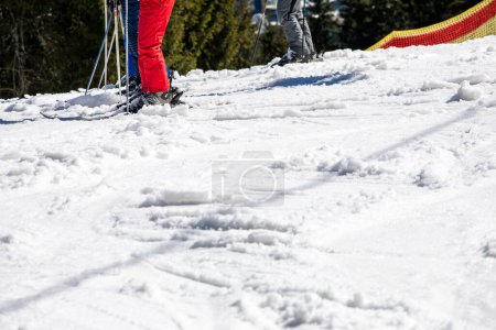 Les skieurs se tiennent debout avant de descendre d'une piste de ski par une journée ensoleillée. Vacances actives en famille