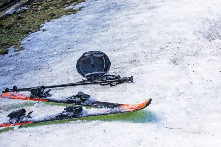 Helm und Skier auf einem verschneiten Hang an einem sonnigen Tag. Freizeit