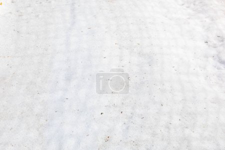 abstrakter Hintergrund aus weißem, nassen Schnee, der von der Sonne beleuchtet wird