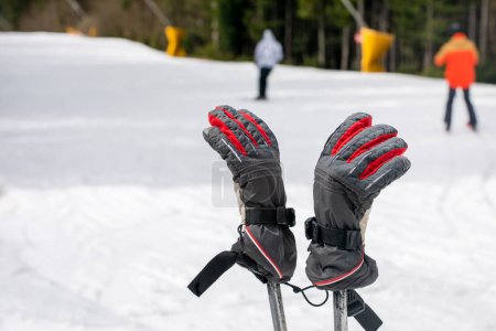 Skihandschuhe an Skistöcken auf der Piste. Freizeit