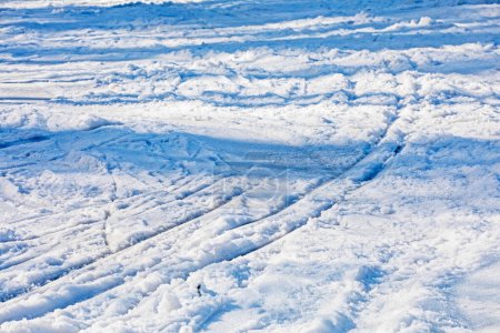 fond de neige blanche avec des traces de skieurs par une journée ensoleillée