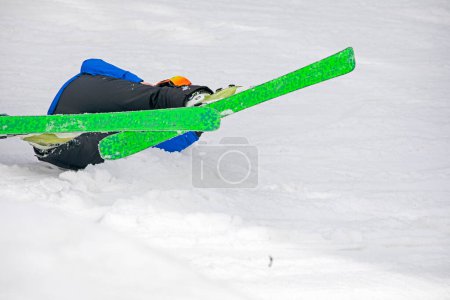 fallen skier on a snowy slope. Active recreation and safety
