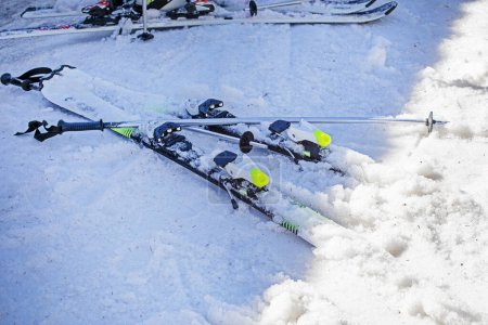 bastones de esquí y esquís en una ladera nevada en un día soleado