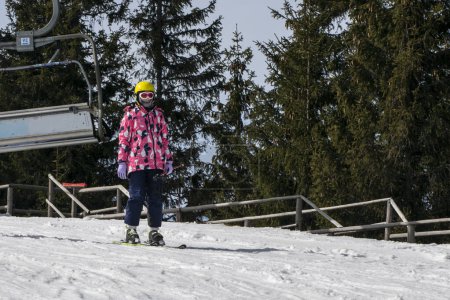 Der junge Skifahrer beginnt, von einem mittelhohen Skihang abzufahren. Aktive Erholung. Gesunder Lebensstil