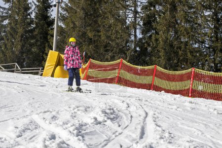 Der junge Skifahrer beginnt, von einem mittelhohen Skihang abzufahren. Aktive Erholung. Gesunder Lebensstil