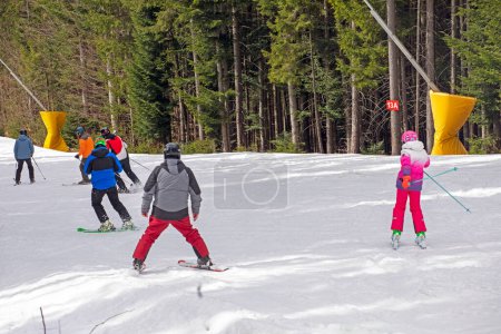 skiers begin to descend from a mid-level ski slope. Active recreation. Healthy lifestyle