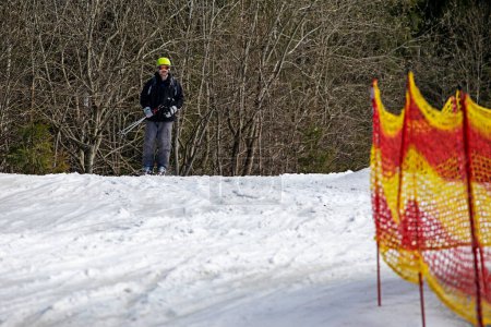 Skifahrer beginnt, von einem mittelhohen Skihang abzufahren. Aktive Erholung. Gesunder Lebensstil