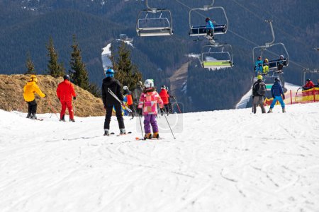 Skifahrer beginnen, von einem mittelhohen Skihang abzufahren. Aktive Erholung. Gesunder Lebensstil
