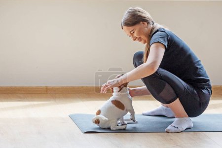 happy girl doing yoga with funny Jack Russell Terrier puppy. Healthy lifestyle