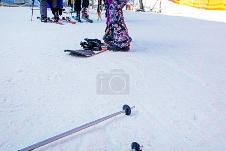 skiers and snowboarders re-strap their boots for a moderately difficult ski slope. Leisure