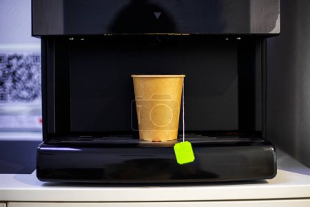 machine with a disposable, recyclable cardboard cup containing a hot drink. Ecology of the environment