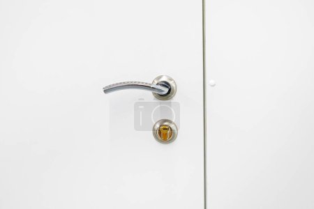 metal handle on a white closed door. Modern interior