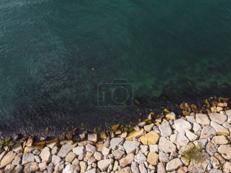 Photo for Large granite stones on the river bank. The edge of the river, reinforced with large stones against erosion. View of stone paving on the embankment, strengthening the river bank. High quality photo - Royalty Free Image
