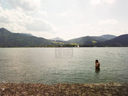 Mann schwimmt während der Sommerferien auf dem Turano-See. Hochwertiges Foto. ein Mann Silhouette im Wasser schwingt, umgeben von Bergen. 