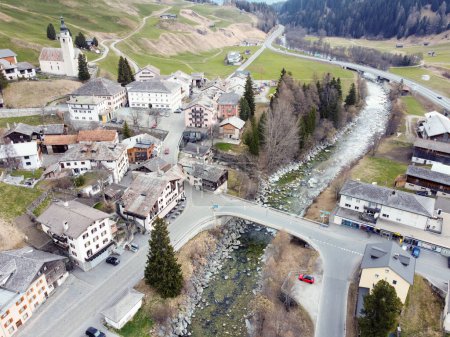El pueblo de montaña de Splugen en Suiza. Foto de alta calidad.Un pequeño pueblo en las montañas, compuesto por casas de madera con techos inclinados. El pueblo está rodeado de verdes campos y árboles. 