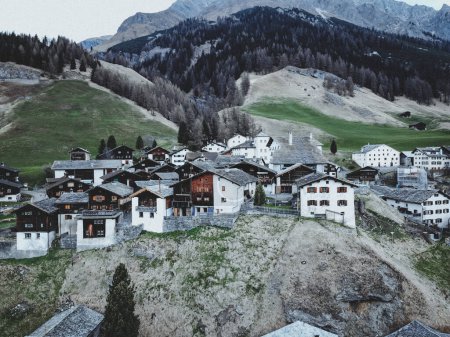 The mountain village of Splugen in Switzerland. High quality photo.a small village in the mountains, made up of wooden houses with sloping roofs. The village is surrounded by green fields and trees. 
