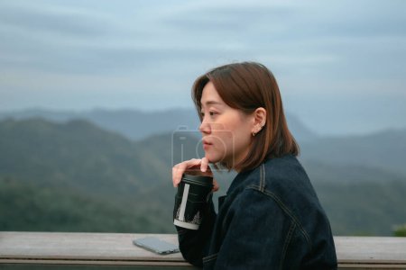 Alleinreisende asiatische Hipster-Frau trinkt Kaffee im Bergblick der Outdoor-Bar des Coffeeshops