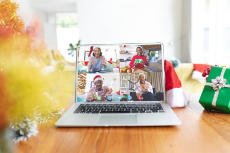 Photo for Happy diverse people with santa hats and christmas decorations having christmas laptop video call. Christmas, celebration and digital composite image. - Royalty Free Image