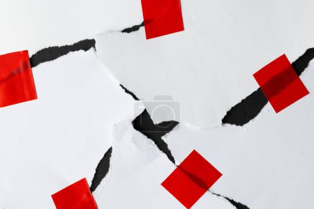 Photo for Ripped up pieces of white paper stuck together with red tape on black background. Abstract paper texture background and communication concept. - Royalty Free Image