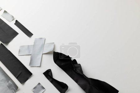 Photo for Pieces of black and grey masking tape and grey masking tape cross on white paper, with copy space. Abstract paper texture, repair and distressed background concept. - Royalty Free Image