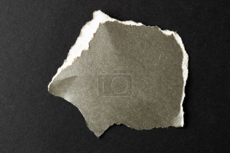 Foto de Pieza rasgada de papel gris con espacio de copia sobre fondo negro. Textura de papel abstracto fondo y concepto de comunicación. - Imagen libre de derechos
