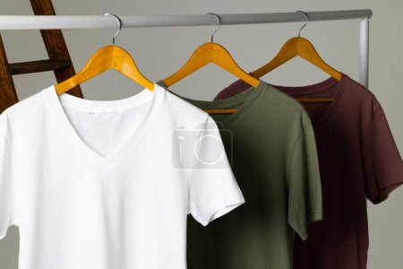 Foto de Camisetas de colores mostradas en la escalera y espacio de copia sobre fondo blanco. Ropa, moda y concepto de retail. - Imagen libre de derechos