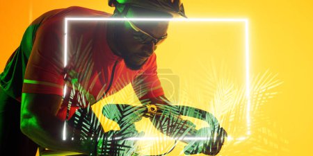 Téléchargez les photos : Vélo cycliste afro-américain masculin par un rectangle éclairé et des plantes sur fond jaune. Espace de copie, composite, sport, cyclisme, course, compétition, nature, forme et concept abstrait. - en image libre de droit