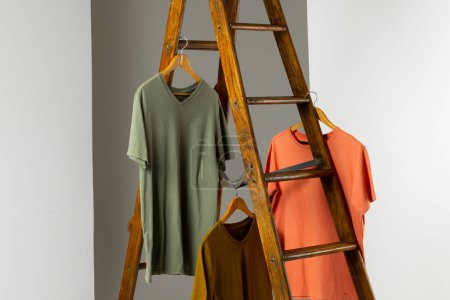 Foto de Camisetas desplegadas en escalera y espacio de copia sobre fondo blanco. Ropa, moda y concepto de retail. - Imagen libre de derechos